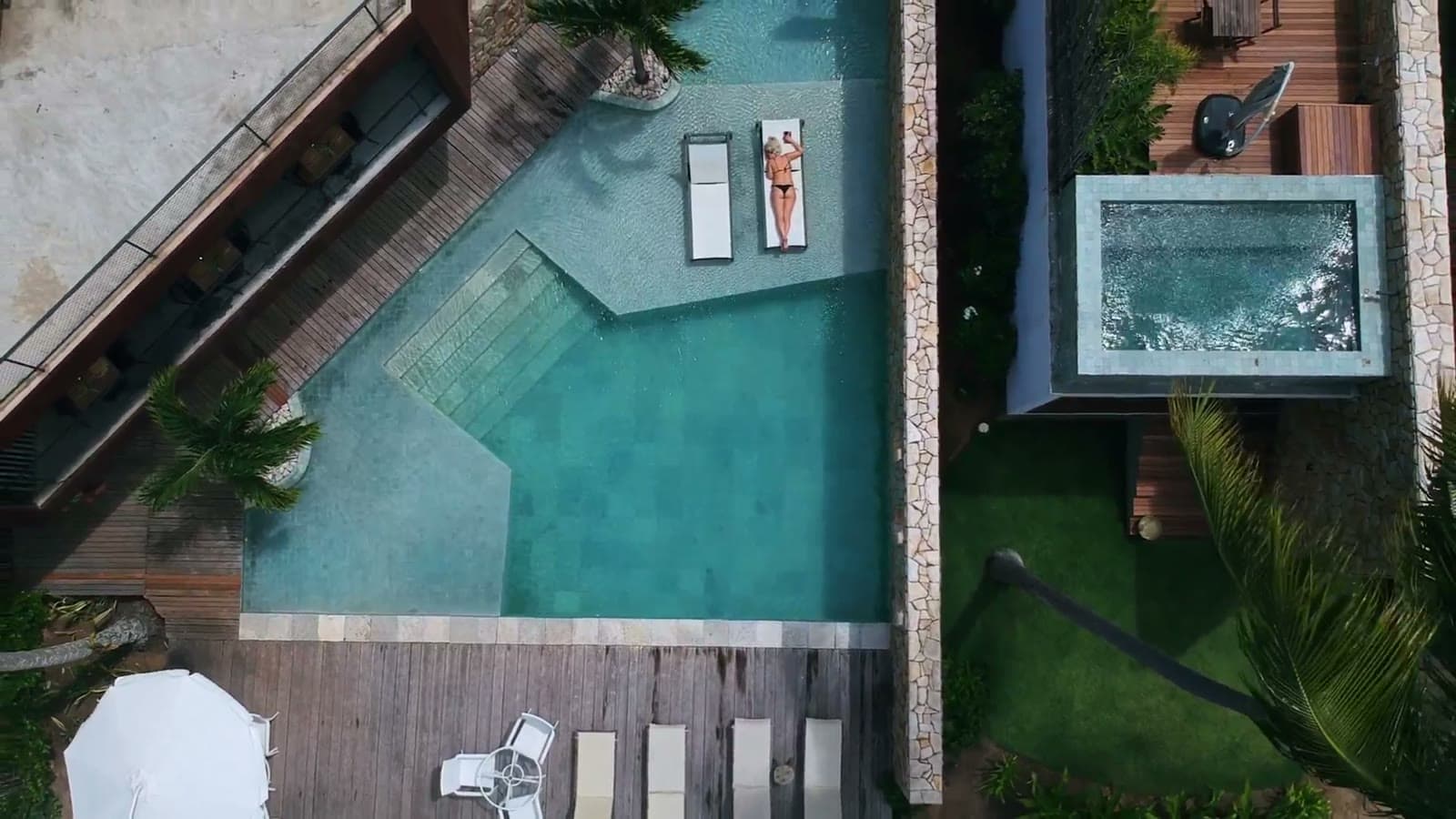 A glass villa at dusk with a mirror-still infinity pool